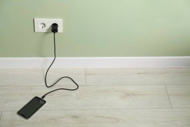 Kablolu USB adaptörü elektrik prizine takılı, akıllı telefonu içeride şarj ediyor. Metin için boşluk