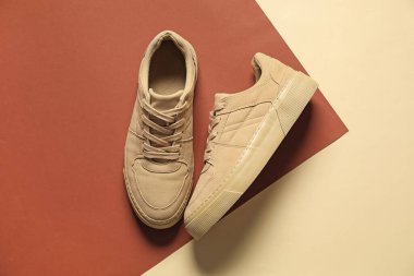 Renkli arka planda bir çift bej spor ayakkabı, düz. Spor ayakkabılar.