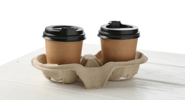 Kağıt kahve bardakları beyaz ahşap masadaki karton tutacakta, yakın plan.