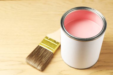 Ahşap arka planda pembe boya ve fırça kutusu, yakın plan.