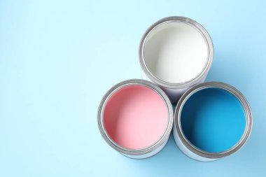 Açık mavi arka planda farklı boya kutuları, düz bir zemin. Metin için boşluk