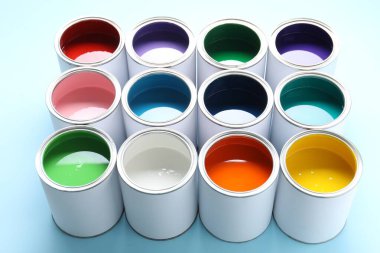 Cans of different paints on light blue background, closeup