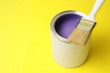 Sarı arka planda menekşe boya ve fırça kutusu, yakın plan. Metin için boşluk