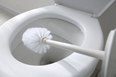 Cleaning toilet bowl with brush indoors, closeup