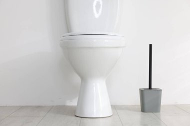 Toilet and brush on floor near white wall