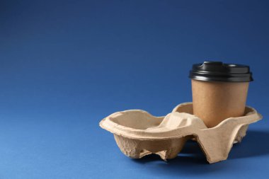 Kağıt kahve fincanı mavi arka planda karton tutacakta. Metin için boşluk