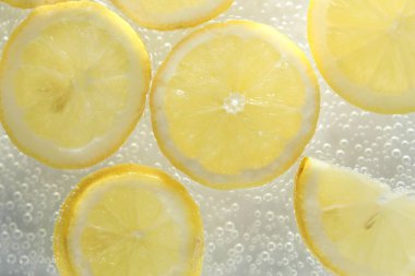 Arka planda limon dilimleri olan soda, yakın plan.