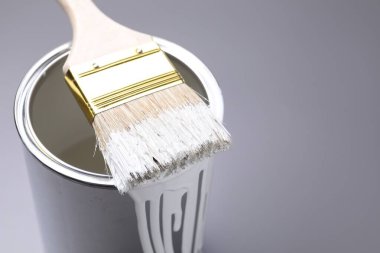 Gri arka planda beyaz boya ve fırça kutusu, yakın plan. Metin için boşluk