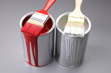 Cans of paint and brushes on grey background, closeup