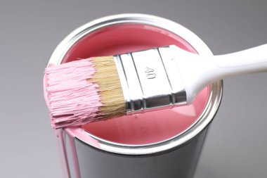 Gri arka planda pembe boya ve fırça kutusu, yakın plan.