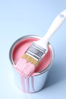 Can of pink paint and brush on light background, closeup