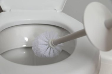 Cleaning toilet bowl with brush indoors, closeup