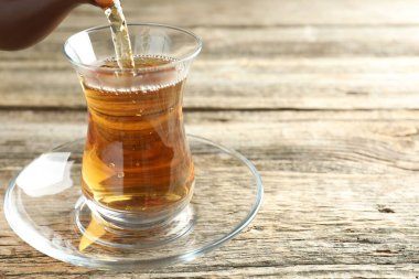 Ahşap masada cama aromatik çay dökmek, yakın çekim. Metin için boşluk