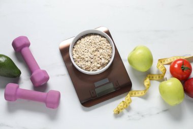 Elektronik mutfak ölçeği, mezura, halterler ve ürünler beyaz mermer masa üzerinde, düz zemin. Diyet