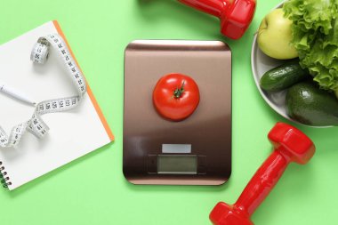 Elektronik mutfak ölçeği, mezura, dambıl, not defteri ve açık yeşil arka plandaki ürünler, düz yatak. Kalori kontrolü