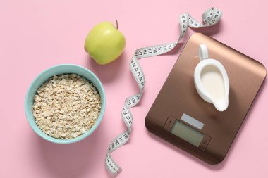 Elektronik mutfak ölçeği, mezura ve pembe arka plandaki ürünler, düz konum. Diyet