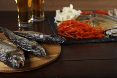 Kurutulmuş balık atıştırmalıkları ve bira ahşap masada, yakın plan.