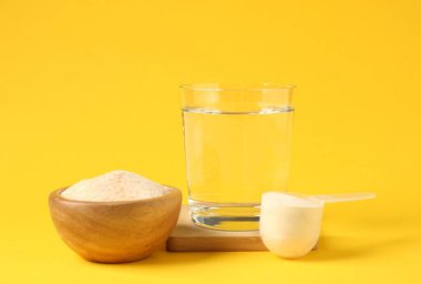 Kasede kolajen tozu, sarı arka planda kepçe ve bardak su.