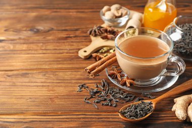 Bardakta Aromatik Masala çayı, baharatlar, kuru yapraklar ve ahşap masada bal, yakın plan. Metin için boşluk