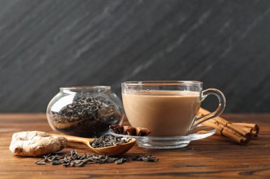 Aromatik Masala çayı, ahşap masada baharatlar ve kuru yapraklar.