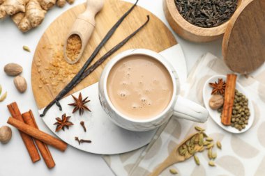 Fincanda Aromatik Masala çayı, beyaz masada kahverengi şeker ve baharatlar, düz uzanmış