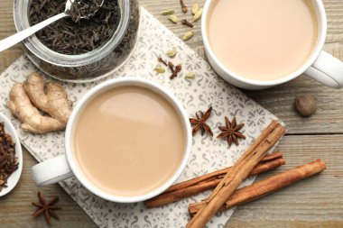 Fincanlarda Aromatik Masala çayı, ahşap masada kuru yapraklar ve baharatlar.