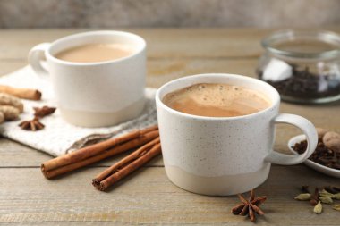 Ahşap masada fincanlarda ve baharatlarda Aromatik Masala çayı, yakın plan