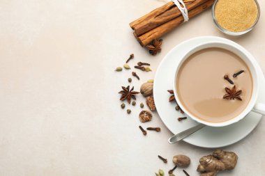 Aromatik Masala çayı bardakta, baharatlar ve kahverengi şeker açık gri masada, düz yerde. Metin için boşluk