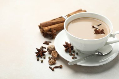 Aromatik Masala çayı fincanda ve baharatlar açık gri masada, yakın plan. Metin için boşluk