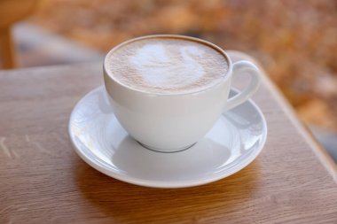 Kafedeki ahşap masada bir fincan aromatik kahve, yakın plan.