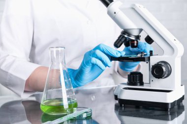 Laboratuvar testi. Bilim adamları kapalı alanda mikroskop altında numuneyi inceliyor.