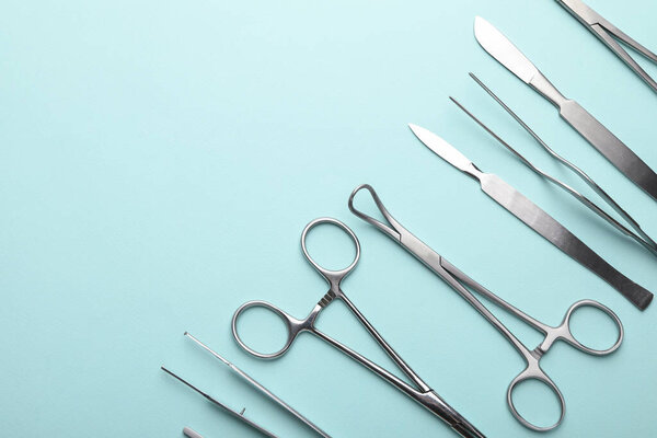 Различные хирургические инструменты на бирюзовом фоне, плоский узор. Пространство для текста