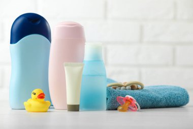 Bebek kozmetik ürünleri, emzik, havlu ve plastik ördek beyaz tuğla duvara karşı, yakın plan.