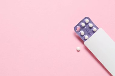 Blister of oral contraceptive pills on pink background, top view. Space for text