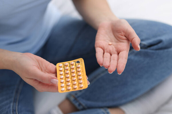 Woman with contraceptive pills on bed, closeup