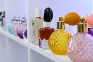 Dükkandaki raflarda farklı lüks parfüm şişeleri var.