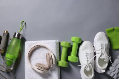 Farklı spor aletleri ve gri arka planda kulaklıklar, düz yatış. Metin için boşluk