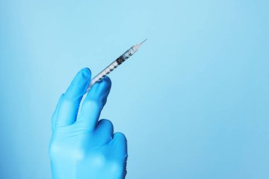 Doktor elinde şırıngayla tozlu açık mavi arka plan, yakın plan. Metin için boşluk