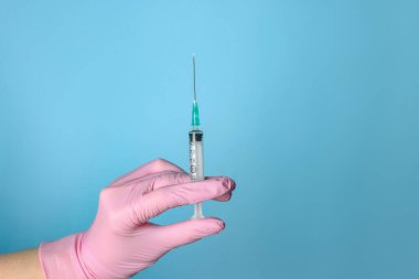 Doktor elinde şırıngayla tozlu açık mavi arka plan, yakın plan. Metin için boşluk