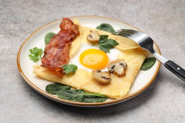 Gri masada servis edilen yumurta, pastırma ve mantarlı leziz krep, yakın plan. Breton galeti