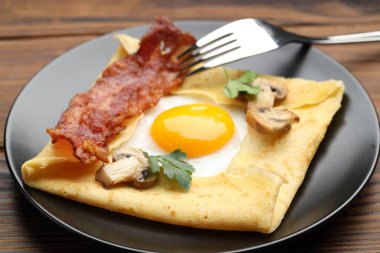 Tahta masada servis edilen yumurta, pastırma ve mantarlı leziz krep, yakın plan. Breton galeti