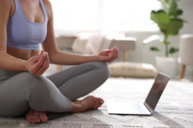 Dizüstü bilgisayarı olan kadın evde meditasyon yapıyor, yakın plan.