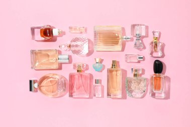 Pembe arka planda çeşitli parfüm şişeleri, düzlük