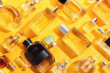 Sarı arka planda çeşitli parfüm şişeleri, düz yatıyordu.