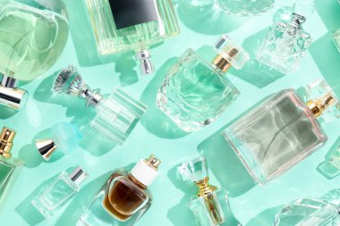 Turkuaz arka planda çeşitli parfüm şişeleri, düzlük