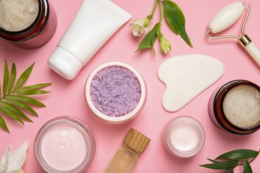 Pembe arka planda farklı vücut bakım ürünleriyle düz konum