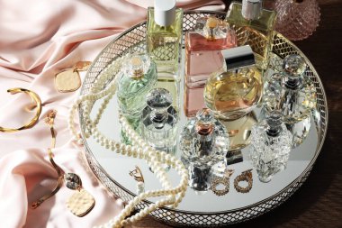 Tahta masadaki farklı lüks parfümler ve aksesuarlar.