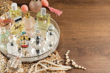 Ahşap masada farklı lüks parfümler ve aksesuarlar, metin için yer.