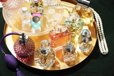 Yeşil pouf 'ta farklı lüks parfümler ve aksesuarlar.