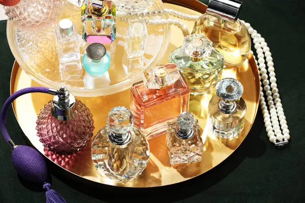 Yeşil pouf 'ta farklı lüks parfümler ve aksesuarlar.